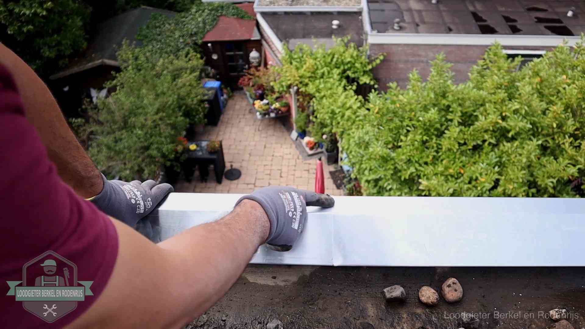 Vakman plaatst een daktrim op de dakrand van een woning in Berkel en Rodenrijs