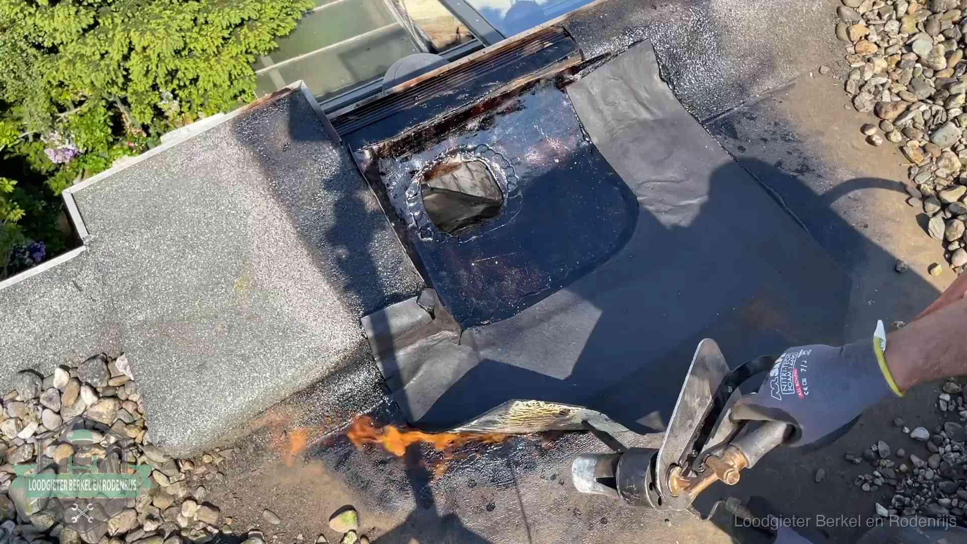 Dakdekker brandt bitumen rond een doorvoer tijdens een daklekkage-reparatie in Berkel en Rodenrijs