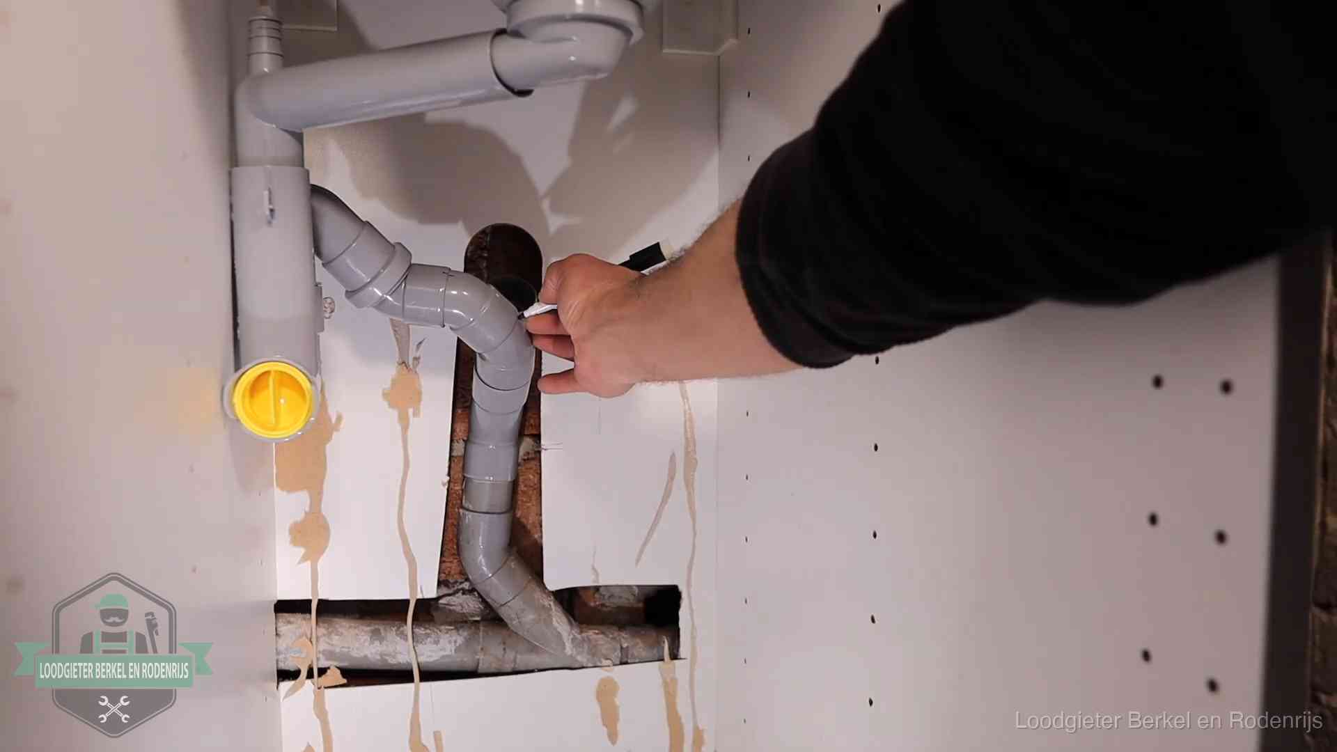 Loodgieter voor verhuurders en bedrijven in Berkel en Rodenrijs Loodgieter markeert een pvc-afvoerbuis onder een gootsteen in Berkel en Rodenrijs