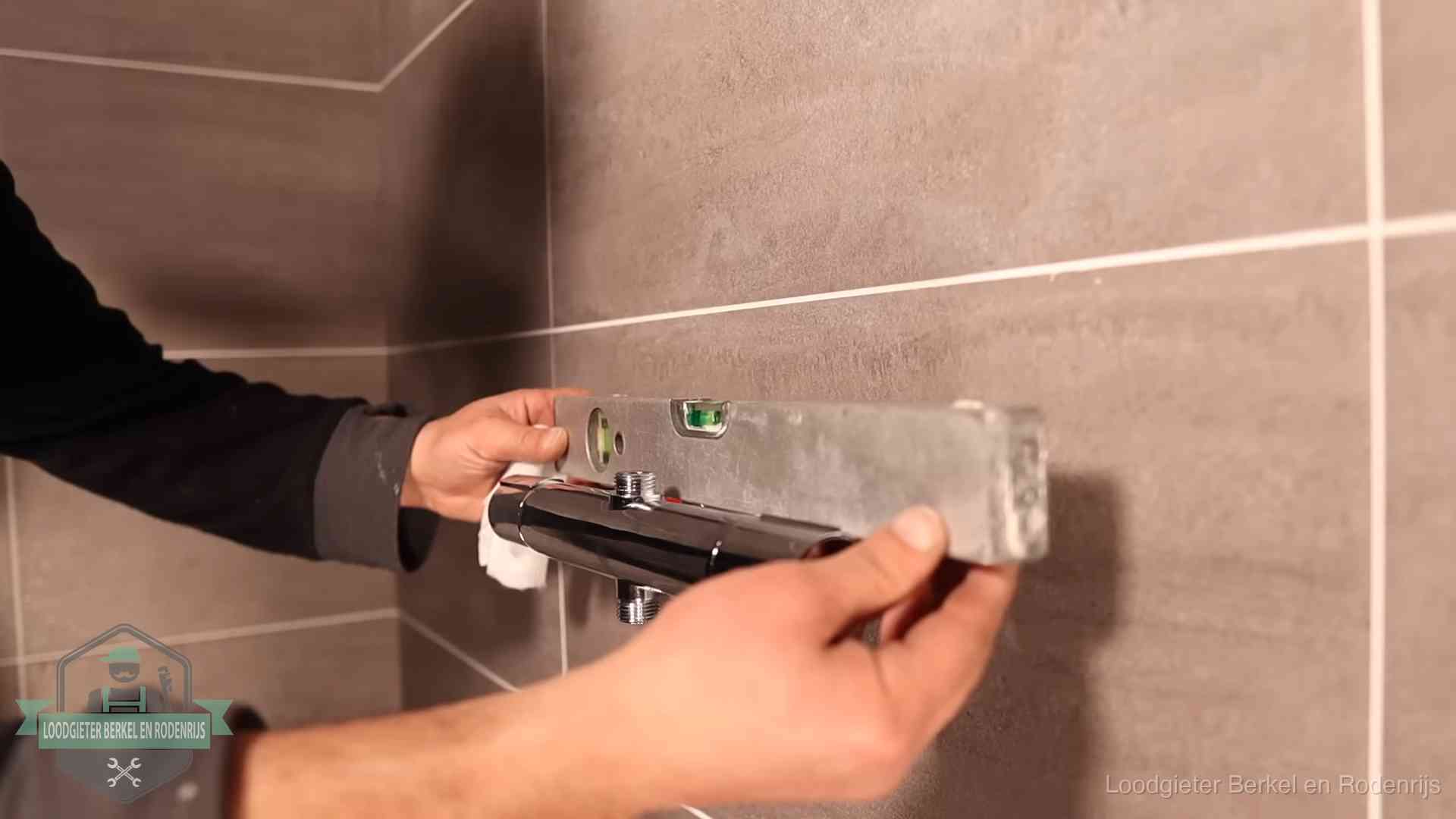 Loodgietersbedrijf voor sanitair in Berkel en Rodenrijs Loodgieter lijnt een douchekraan uit met een waterpas in een woning in Berkel en Rodenrijs