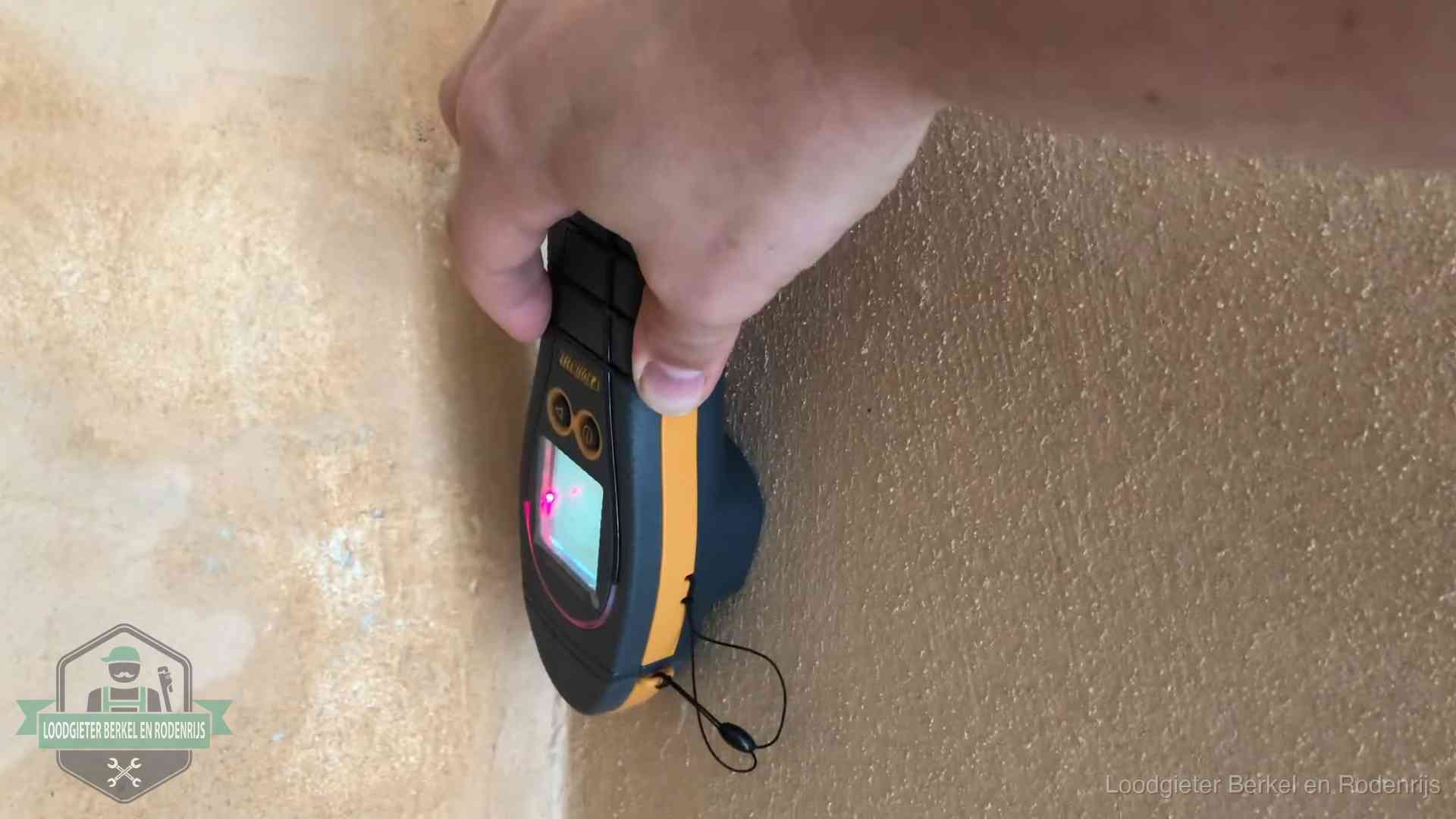 Vochtmeter tegen een muur met vochtplekken tijdens het opsporen van een daklekkage in Berkel en Rodenrijs