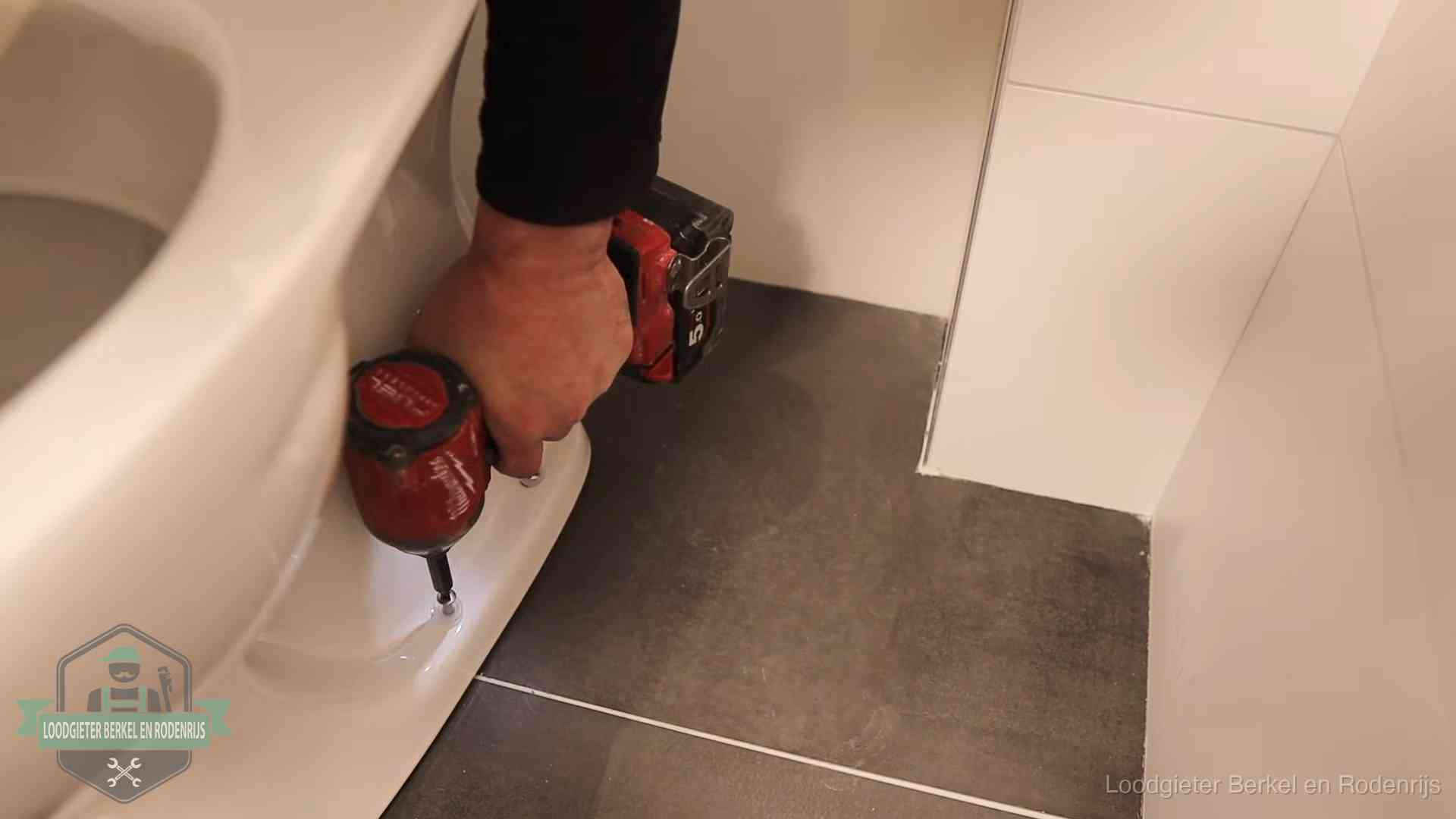 Kosten wc ontstoppen in Berkel en Rodenrijs Loodgieter zet de voet van een wc-pot vast op de tegelvloer in Berkel en Rodenrijs